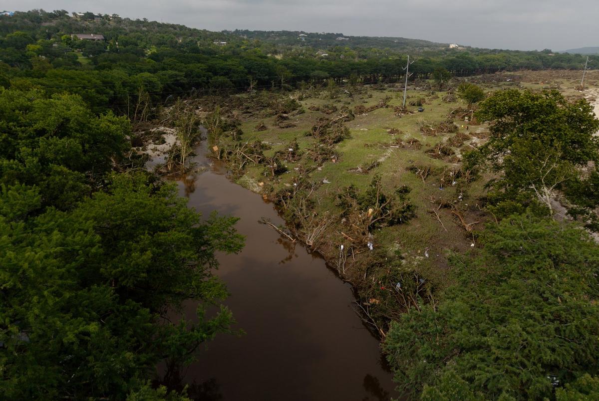Trees uprooted by floodwaters lie across a field in Hunt in Kerr Country on July 5.