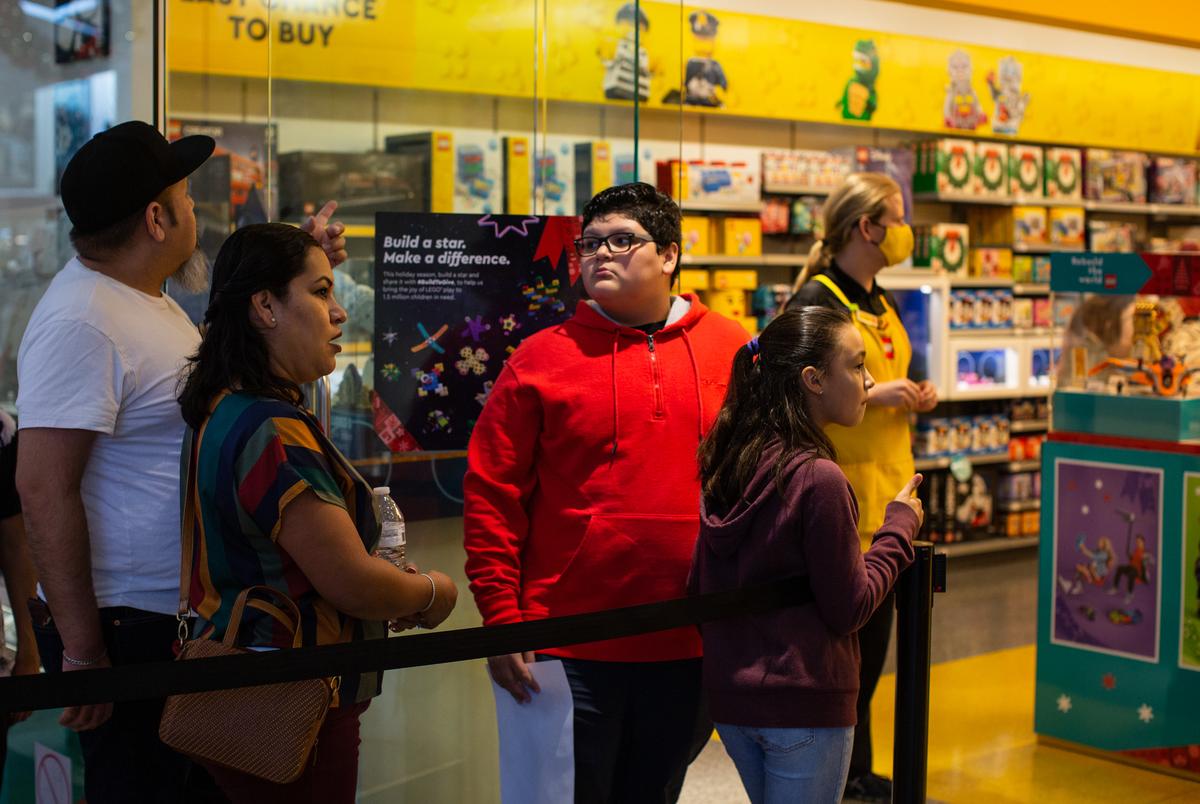 A family waited to enter the Lego store in compliance with social distancing recommendations at the North Star Mall in San Antonio on Dec. 23, 2021. Thousands of people filtered through dozens of stores while hundreds waited in lines to comply with social distancing inside some shops.