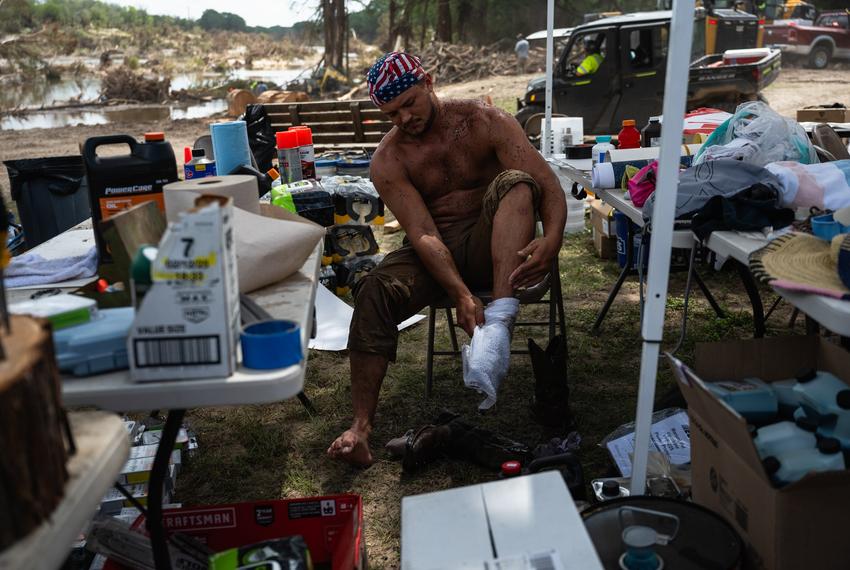 Wyatt Melton, a volunteer from Buda, changes out his soaked socks while aiding in cleanup and recovery efforts at Camp CAMP, a summer camp for people with disabilities organized by Children's Association for Maximum Potential, following the Kerr County flood on Friday, July 11, 2025, in Center Point. Cord Shiflet, a fellow volunteer, made a post on Facebook calling for volunteers to help clean the camp’s riverfront and since it has been published, over 1,000 volunteers have offered their time and resources.