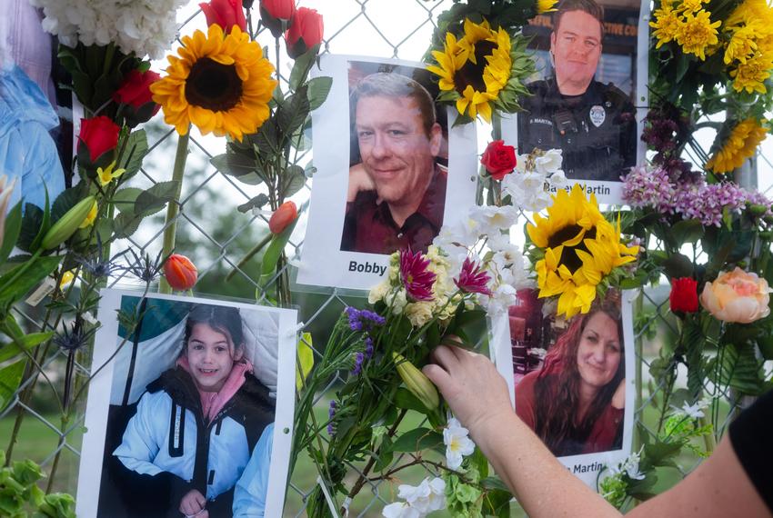 Photos and flowers hang on a fence as a memorial to flood victims.