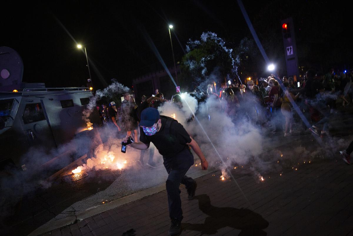 Protesters run away as Dallas police officers launch tear gas after a confrontation during a rally for George Floyd on May 29, 2020.