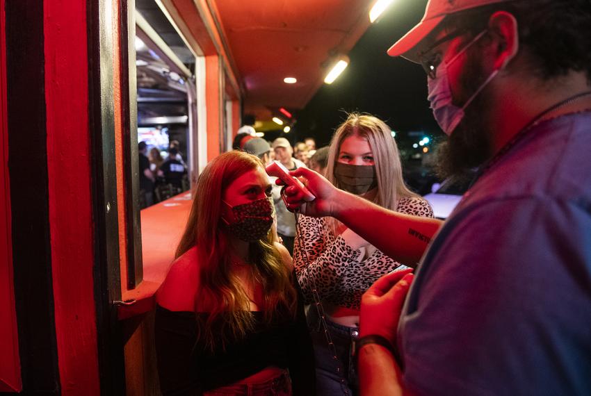 A doorman takes temperatures outside of Mesquites Bar and Grill before customers entered in Lubbock on Oct. 17, 2020. 