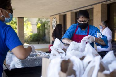 Round Rock ISD food service worker Hema Patel prepares meals to distribute to families during a curbside meal distribution at Bluebonnet Elementary School on Aug. 20, 2020 in Round Rock.