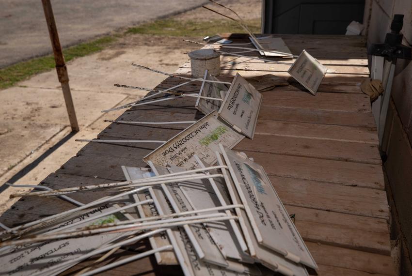 Stacks of temporary grave markers reading “John Doe” and including a migrant’s case number are stacked next to the office building at the Maverick County Cemetery in Eagle Pass on Jan. 10, 2023. The South Texas Human Rights Center and Texas State University’s Operation Identification teams are exhuming several rows of unidentified migrants buried under the signs in an attempt to match descriptions of personal items with Customs and Border Protection case numbers.