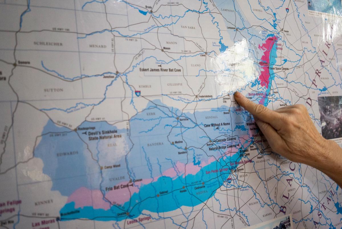 Annalisa Peace, Executive Director at Greater Edwards Aquifer Alliance, discusses concerns of impervious cover and downstream flooding while pointing at a Greater Edwards Aquifer map displayed at the nonprofit’s headquarters in San Antonio on June 14, 2023. “The Edwards is one of the most prolific water systems in the world,” Peace said. While Peace says the Edwards is a bounteous resource, it’s also “incredibly vulnerable to pollution.”