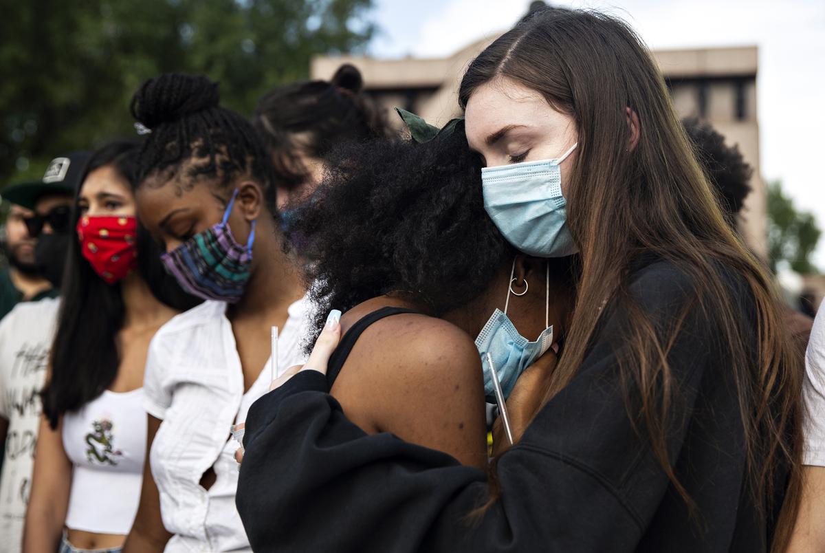 Taylor Putnam comforts her friend Veronica Holmes at a vigil honoring those whose lives were lost to police shootings at Freedman's Memorial Cemetery on May 31. 