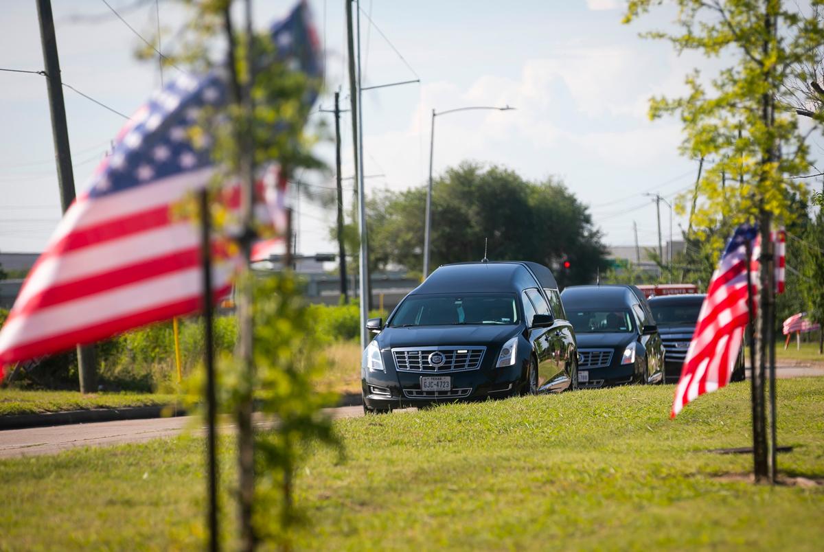 A hearse containing the body of George Floyd drives up a flag-lined street as it approaches the Fountain of Praise Church in Houston on June 8, 2020.