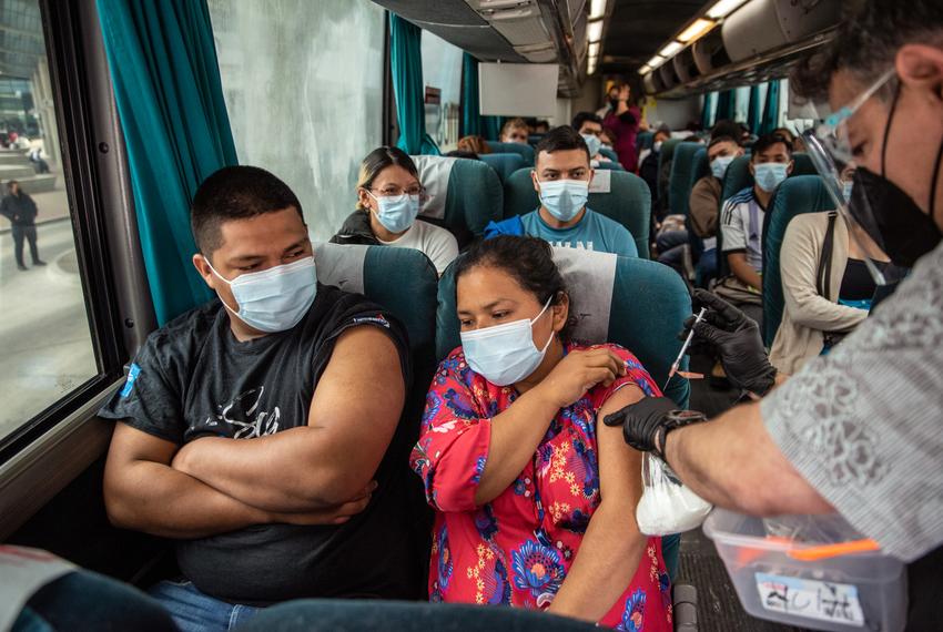 Victor Trevino administers a vaccine against COVID19 to Yaidra Lucas inside a bus on Thursday, March 3rd, 2022 in Laredo, TX. Workers from Nuevo Laredo were transported to the international crossing point to receive vaccines against COVID19 as part of a program where left over vaccines from the U.S. were to be used instead of being wasted or expiring. Sergio Flores for The Texas Tribune