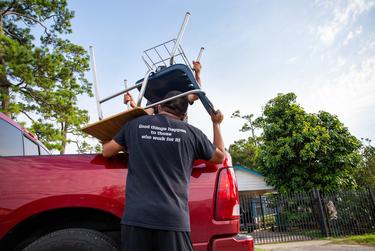 Jesus Sanchez, math instructor at Raul Yzaguirre School for Success, helps load chairs and desks into vehicles during the Drive-Thru Student School Supply Giveaway in Houston on Aug. 22, 2020.