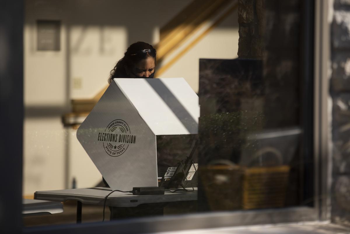 A voter casts their ballot at a polling site at the Austin Oaks Church on Oct. 14, 2020.