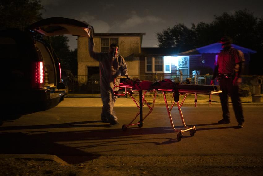 Juan Lopez wheels a stretcher out of the back of his vehicle in the early morning in McAllen. Lopez is picking up the body of a person who recently passed away from COVID-19. July 17, 2020. 