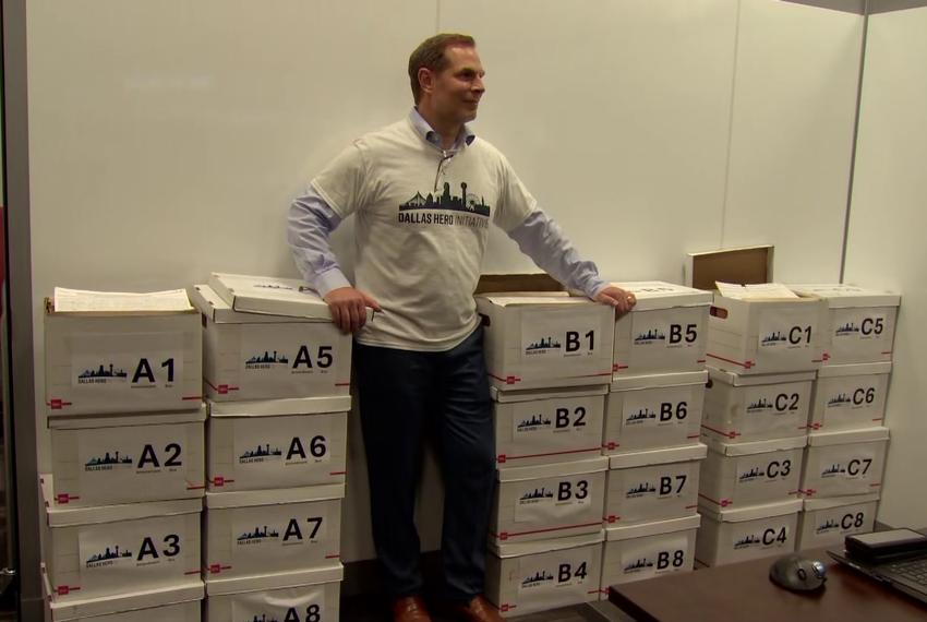 Pete Marocco stands beside boxes of signatures used to get the Dallas HERO propositions, aimed at changing the Dallas city charter, on the November 2024 ballot.