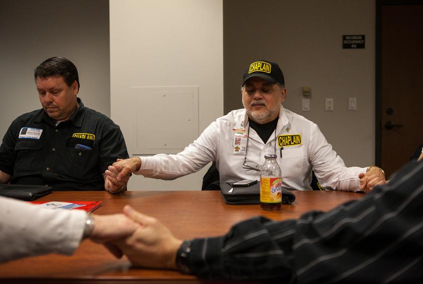 Michael Tummillo (right), the official volunteer chaplain at the Texas Department of Agriculture,  joins hands in prayer with attendees at a weekly "Faith at Work" gathering at the Stephen F. Austin state office building.