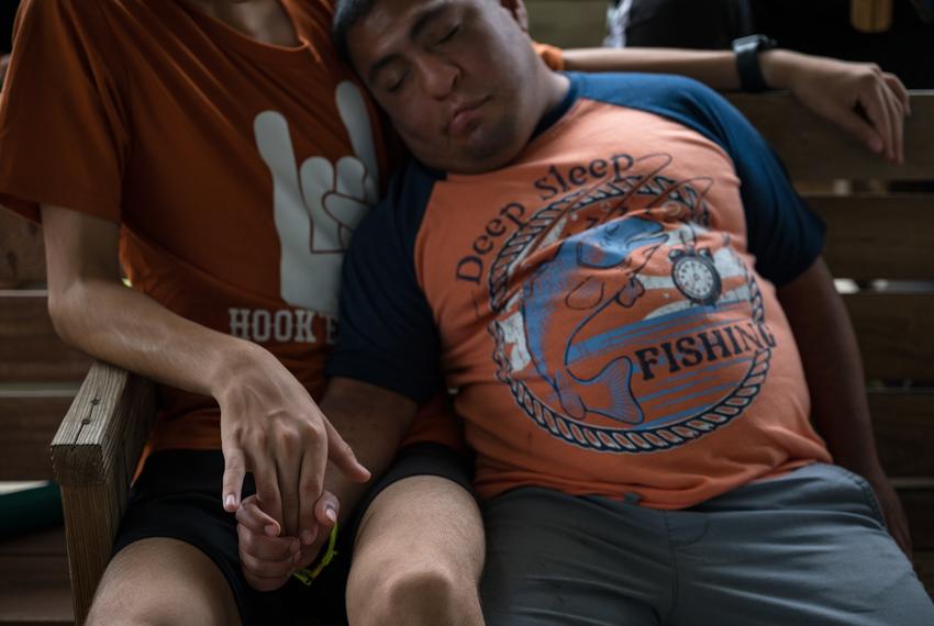 Mario, a camper at Camp CAMP, right, holds hands with his counselor, August, as he takes a nap during Target Sports hour on Tuesday, July 22, 2025, in Center Point. Camp CAMP is a summer camp hosted by Children’s Association for Maximum Potential for people with disabilities and reopened shortly after the July 4th flooding in order to provide a normal summer experience for their campers. Some guardians, such as Mario’s, elected to not send their family members to camp immediately following the flood, but instead sent them after the disaster response normalized.