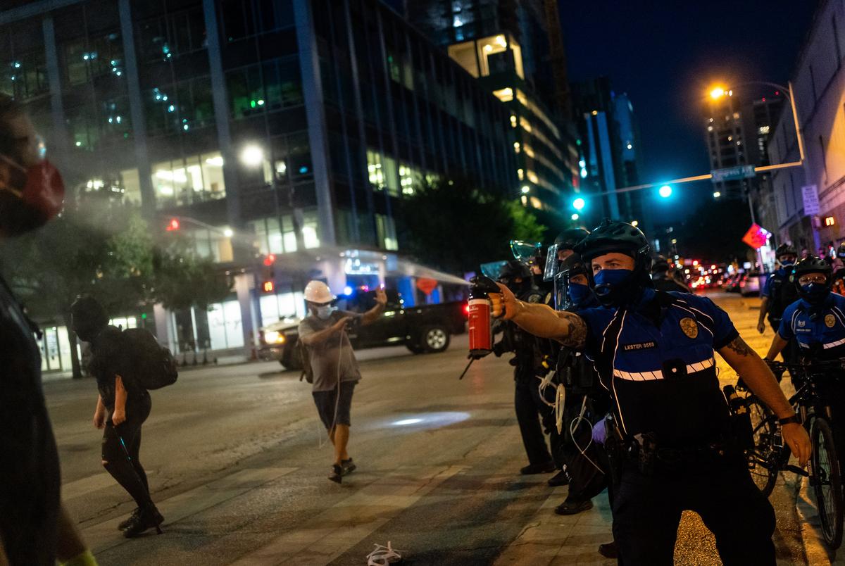 A police officer sprays a protester with pepper spray as demonstrators clash with police in riot gear in downtown Austin on August 1, 2020.