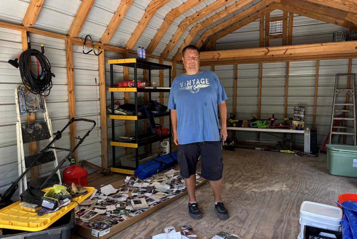 Jason Hefner stands beside water-damaged mementoes in a shed volunteers returned to the slab where his garage once stood. His family lost the garage, its contents — including a beagle — and his mobile home also flooded. Flood insurance, he said, is “unheard of” in the area.