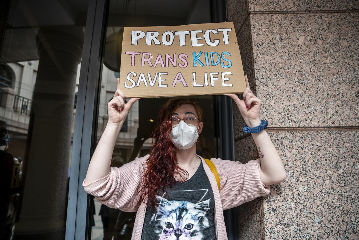 Ada-Rhodes Short holds up a sign that reads 