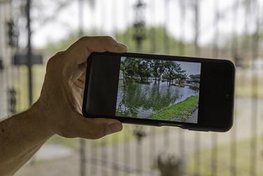 Nueces County resident Dan Zamora holds his phone with a picture of flooding in front of his house last year on May 3, 2022. For the first time since moving here 30 years ago, Zamora's home flooded twice last year. 