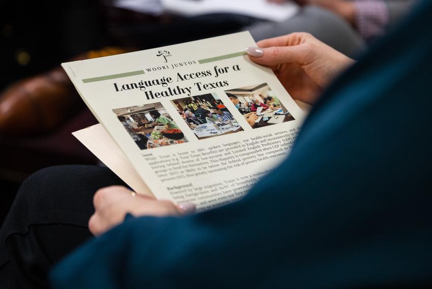 An aide of state Rep. Tom Oliverson, R-Cypress, examines an info sheet while Sarah Syed explains their proposal to create language access plans for health services, on Feb. 9 2023.