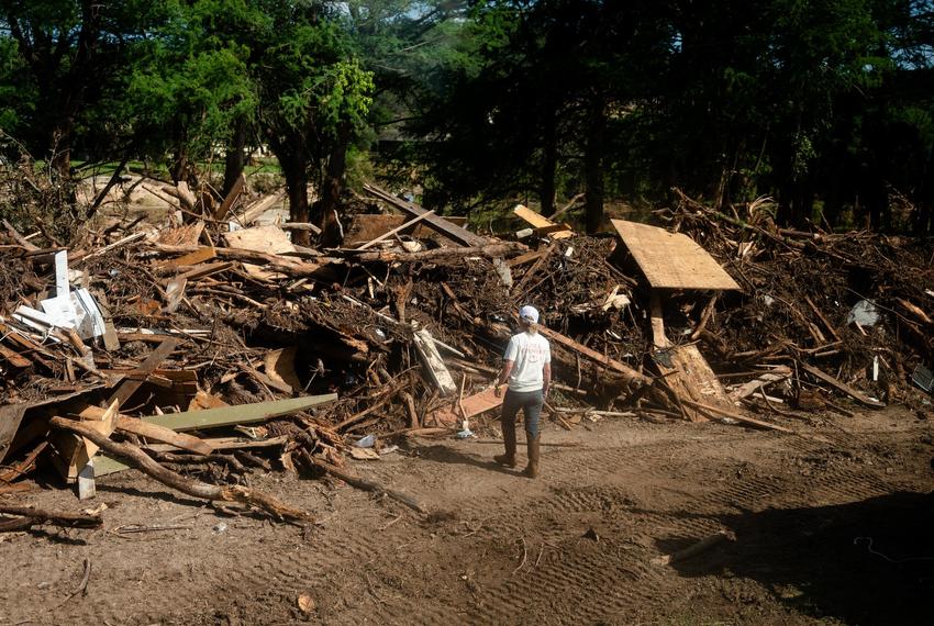 A woman looks at a pile of debris in Hunt on July 8, 2025.