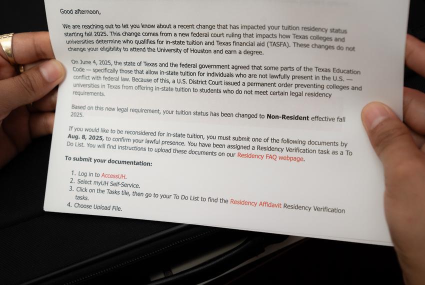 Katerin M.S., 24, a graduate student in social work at the University of Houston, works full time as a case worker while managing her schoolwork in her office. She holds a copy of the email she received from the university requiring nonresident tuition on Sunday, Aug. 17, 2025, in Houston.
