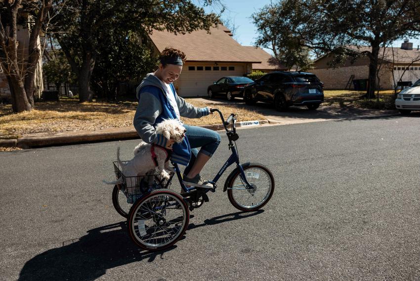 Cass Crawford rides their bike with their two dogs near their home in Austin on Mar. 15, 2022.