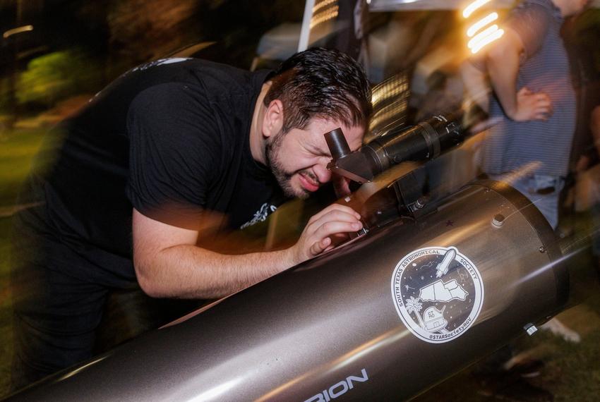 Victor De Los Santos, board chair and co-founder of the South Texas Astronomical Society organization, adjusts a telescope setup for passersby to see stars at a night market in Brownsville on Sept. 20, 2025.