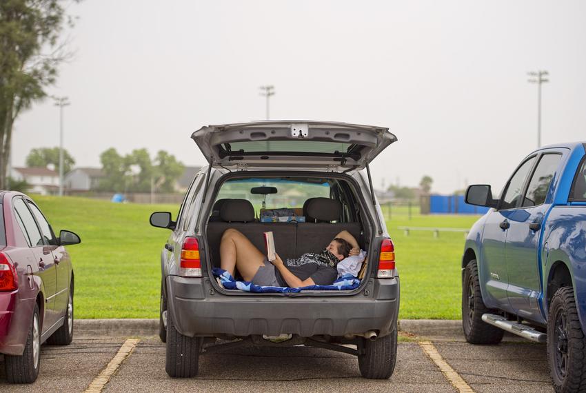 A woman reads in her car while waiting to get tested at the Portland Community Center.