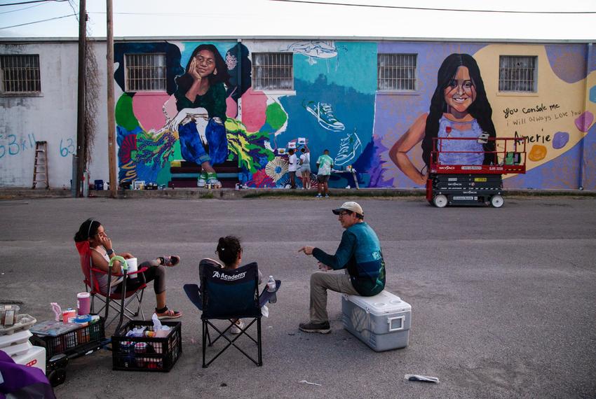 Artists Gabi Magaly, Ana Hernández, and Abel Ortiz-Acosta talk and take a break while family members of Maite Rodriguez work to paint a small section of the mural in her memory in Uvalde July 24, 2022.