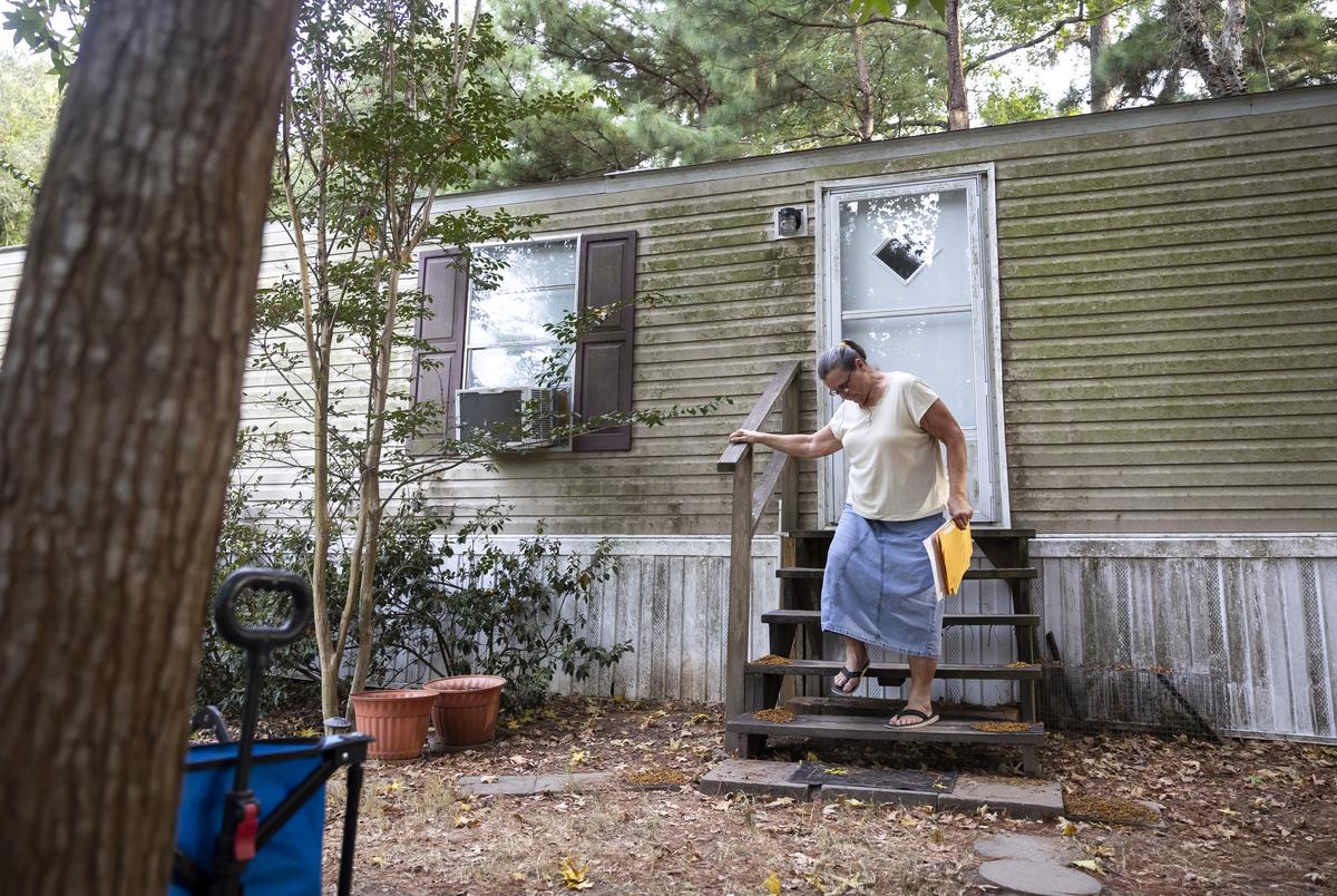 Jinelle “Linda” Lawrence carries paperwork outside of her home along highway TX-105 on August 22, 2023.